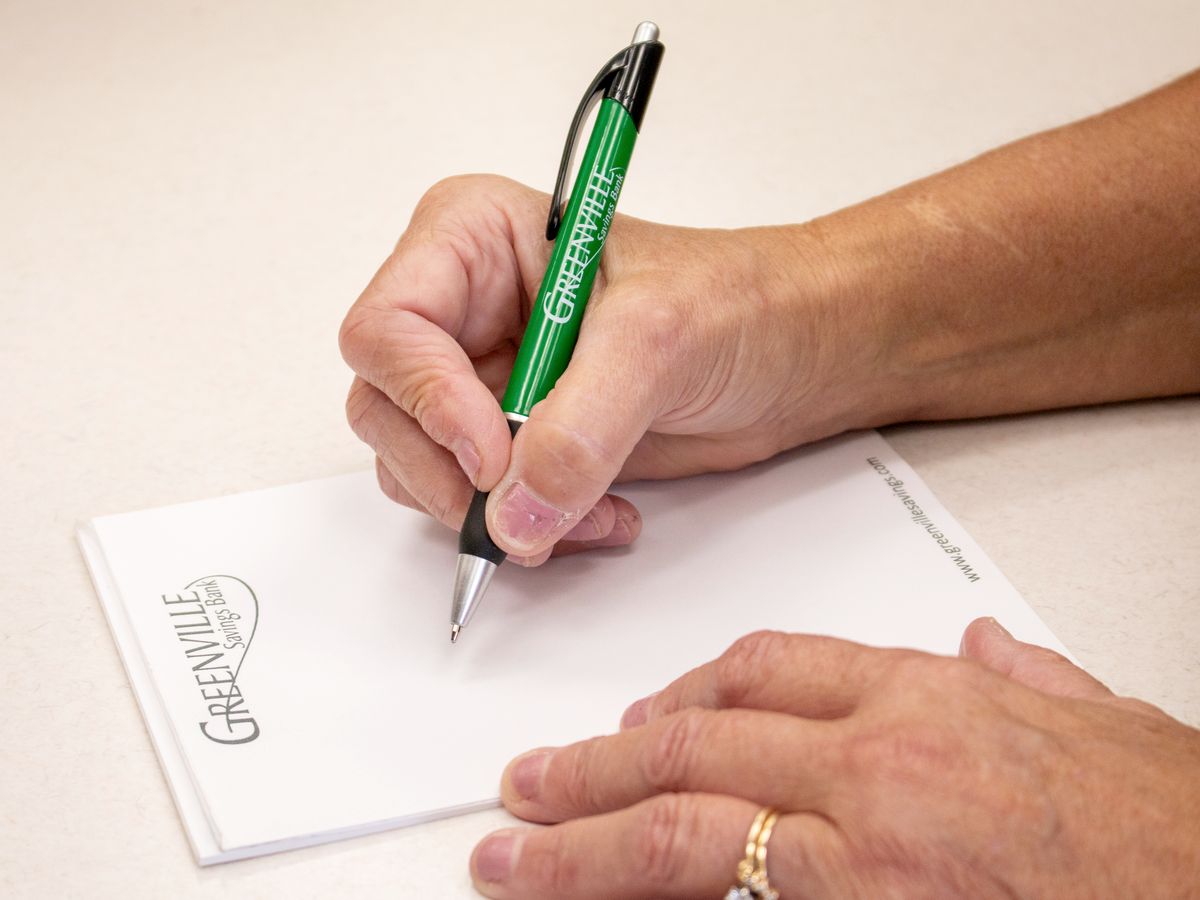 Signing paperwork with a Greenville Savings Bank pen