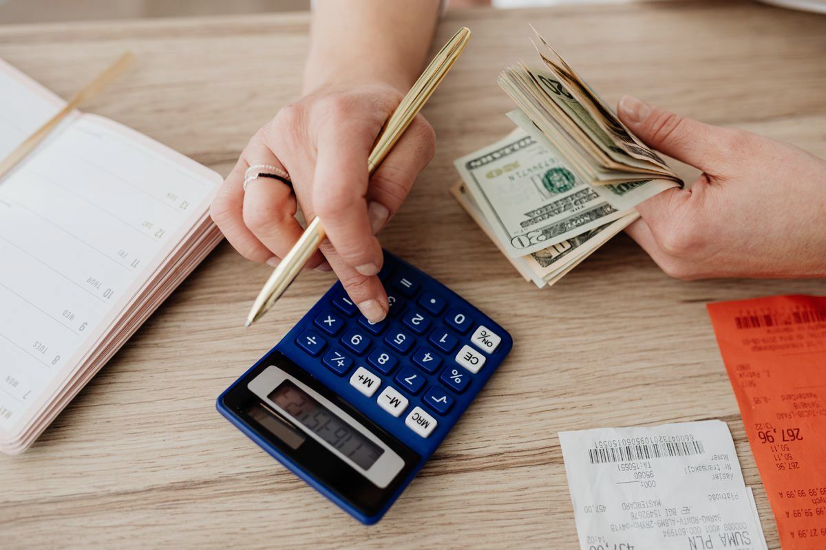 Hands managing everyday spending with a calculator and cash