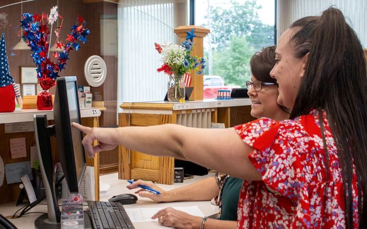 A Greenville Savings Bank teller helping two customers at the counter
